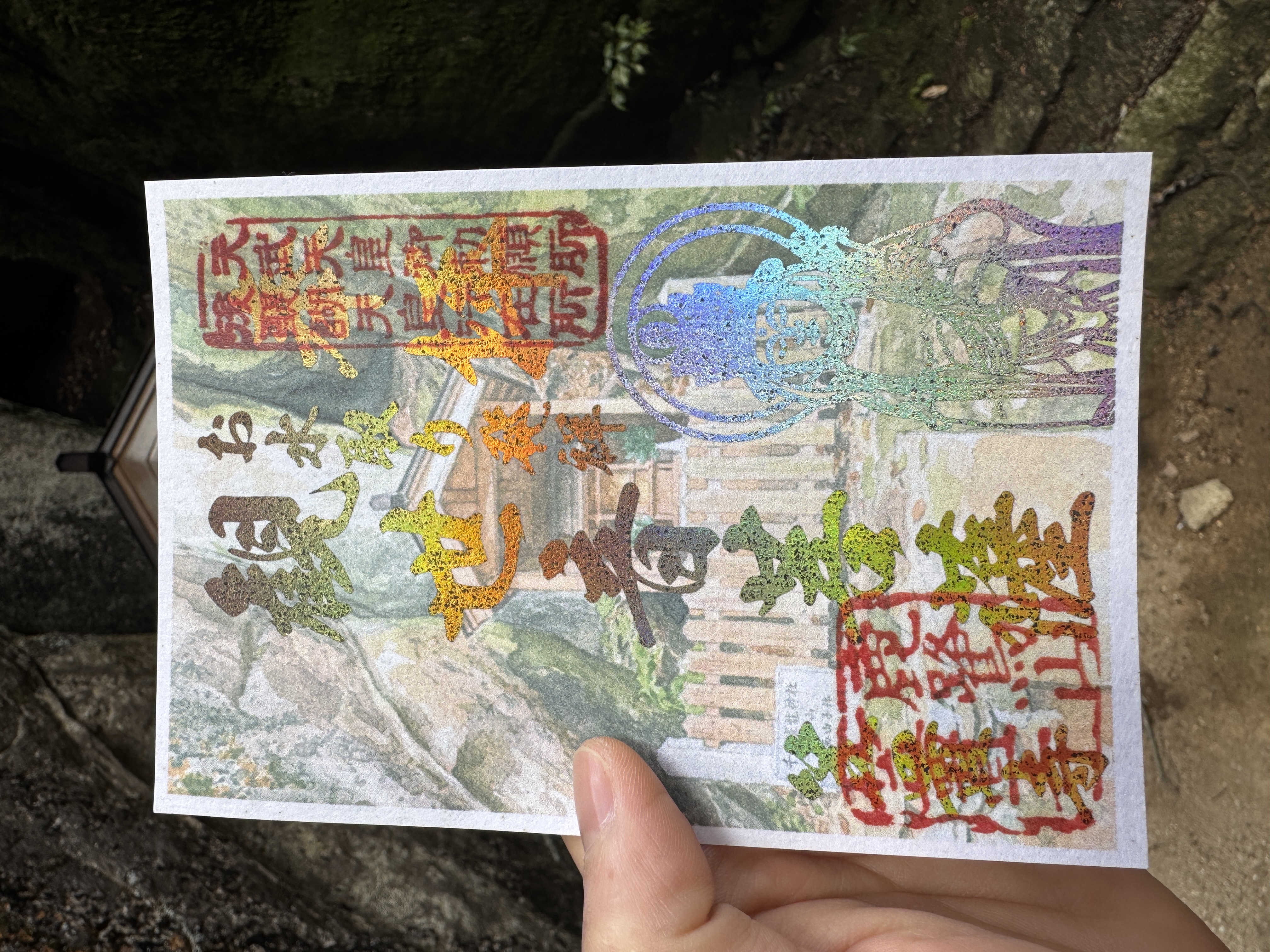 笠置寺の3月限定御朱印。背景に修行場「千手窟」の風景、右下に十一面観音菩薩の線画、中央に「お水取り発祥の地」の文字が箔押しされた御朱印。